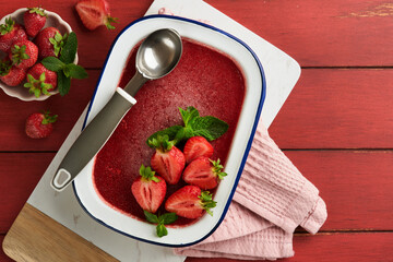Strawberry granita or fresh berry sorbet in white rustic bowl on old wooden table background. Ice cream with strawberry and mint. Summer treat. Top view. - obrazy, fototapety, plakaty