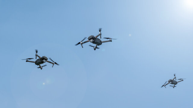 Three surveillance drones in front of blue sky