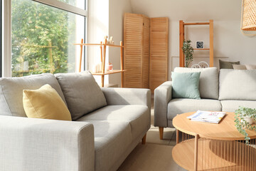 Interior of light living room with cozy grey sofas and wooden coffee table