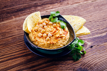 Traditional Indian chickpeas dip with pita bread and herbs as close-up in a design bowl with copy space 