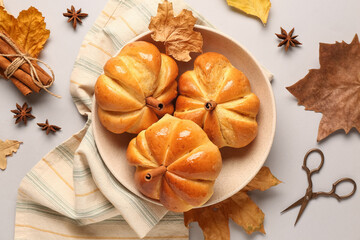 Bowl with tasty pumpkin shaped buns on grey background