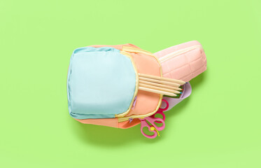 Color school backpack with different stationery on green background