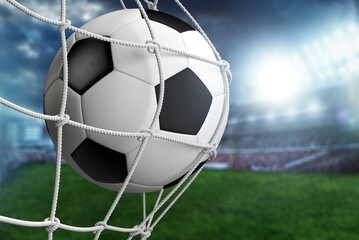 Soccer ball in net in a big green stadium.