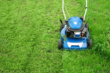 Lawn mower cutting grass. Small grass cuttings fly out of lawnmower. Grass clippings get spewed out of a mower pushed around by landscaper. CloseUp. Gardener working with mower machine. Mowing lawns