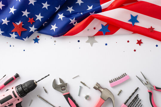 Paying tribute to female workers on Labor Day. Top view image of an American flag accompanied by pink building tools on white isolated background. Perfect for advertisements or text placement