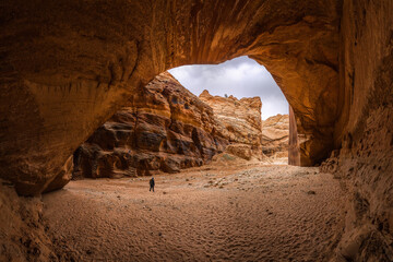 Anonymous tourist with backpack admiring views under rocky mountains