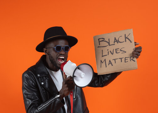 Serious black man in black leather jacket with hat protesting with placard