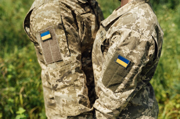 Armed Forces of Ukraine. Married couple in military uniform with a pixel pattern hold hands.