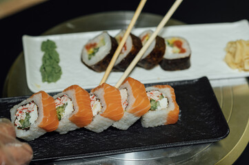 Tasty sushi rolls, wasabi, ginger and soy sauce on black gray table