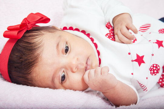 Close up of a sweet one month baby girl wearing a red and white christmas tshirt.