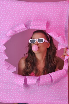 jovem mulher da moda retr&ocirc; fazendo bolha com chiclete em fundo rosa 