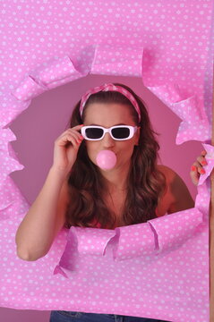 jovem mulher da moda retr&ocirc; fazendo bolha com chiclete em fundo rosa 