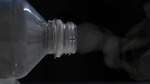 Smoke comes from a plastic bottle, close-up. Burning plastic waste concept