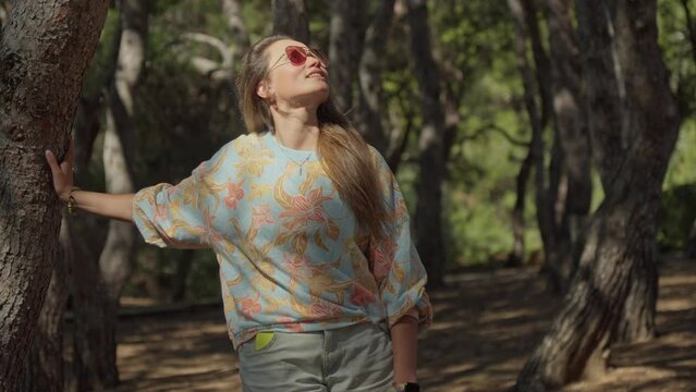 A woman standing in a forest holding a frisbee