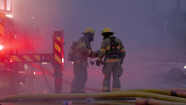 Firefighters and fire trucks battling a raging fire, emergency services, first responders, smoke, water, BC. 4K 24FPS