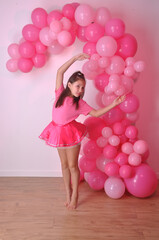 Fototapeta premium menina bailarina feliz com fundo de balões cor de rosa , expressão positiva 