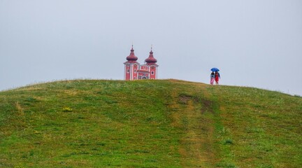Spring landscape with young people. In the background a historic chapel. Two towers on hill over...