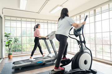 Fototapeta premium Asian cute young lady and senior old asian lady exercise, workout on treadmill or workout equipment together in the gym for healthy life concept.