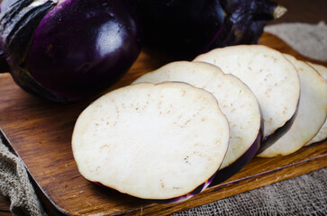 Fresh Sliced Eggplants over Wooden Rustic Background, Purple Round Eggplants