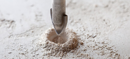 metal drill bit make holes in concrete wall on industrial drilling machine with shavings. Metal...