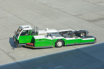 Airplane green tow tractor at the airport apron near the terminal