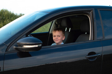 Little boy in the car is happy at the wheel of car holding steering wheel