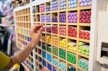 Close-up pupil's hand taking out a watercolor marker from the shelf in school stationery store. Drawing tools. Sketching