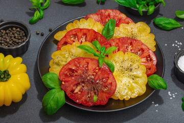 Colorful Heirloom tomato harvest. Ripe ribbed vegetables with fresh basil leaves. Wooden background