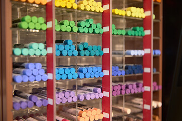 A shelf with colorful pastel crayons of vibrant colors displayed for sale in the school stationery store. Drawing tools