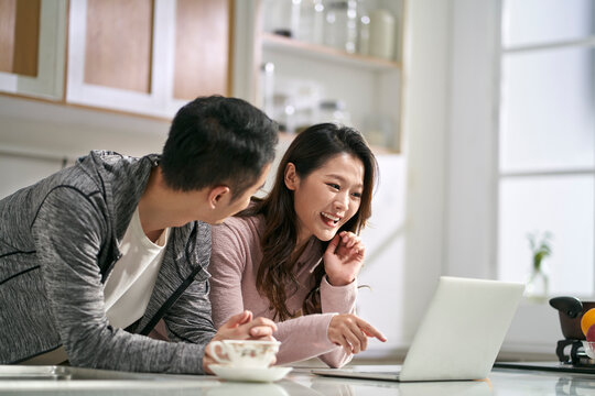 Young Asian Couple Using Laptop Computer Together At Home