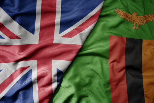 big waving national colorful flag of great britain and national flag of zambia .