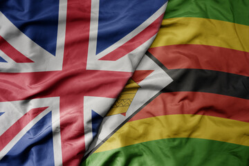 big waving national colorful flag of great britain and national flag of zimbabwe .