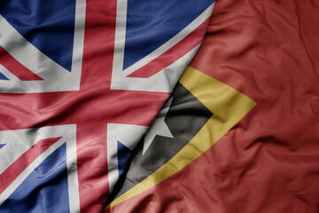 big waving national colorful flag of great britain and national flag of east timor .