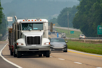 A Loaded Flatbed Eighteen-Wheeler Leads Traffic On A Foggy Day
