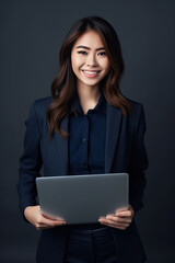 A beautiful smiling asian saleswoman , with arms folded , Holding MacBook，a dark blue suit, a smile on her face, light gray background,generative ai