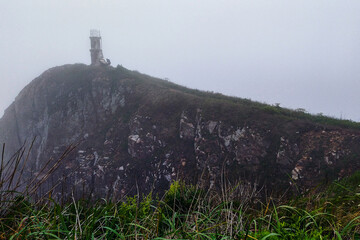 An old abandoned lighthouse on an island shrouded in heavy fog.