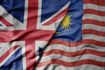 big waving national colorful flag of great britain and national flag of malaysia .