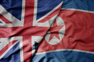 big waving national colorful flag of great britain and national flag of north korea .