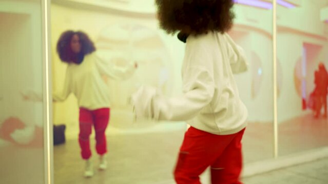 mid adult black woman afro hair dancing freestyle indoors in front of a mirror	