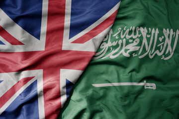 Fototapeta premium big waving national colorful flag of great britain and national flag of saudi arabia .