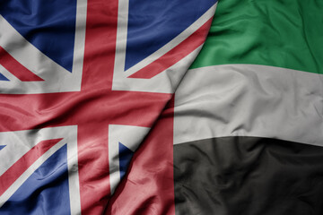 big waving national colorful flag of great britain and national flag of united arab emirates .
