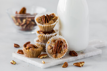 A close up of a pile of salted caramel pecan tarts with a bottle of milk.