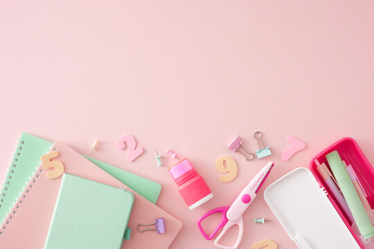 Stationery for school concept. Top view flat lay of notepads, trendy pencil case, colorful numbers, scissors, pens, marker, binder clips, pins on pastel pink background with empty space for ad or text
