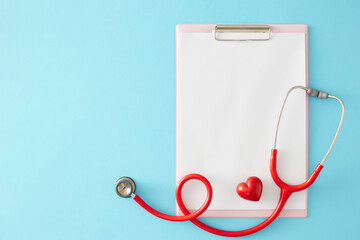 The concept of importance of taking care of heart health. Top view arrangement of blank clipboard, stethoscope, red heart on pastel blue background with empty space for promo or message