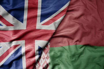 big waving national colorful flag of great britain and national flag of belarus .
