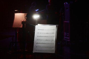 Illumination of the music stand with notes on the stage. Before a concert or orchestra rehearsal