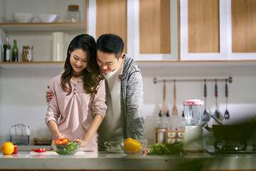 young asian couple preparing meal in kitchen at home