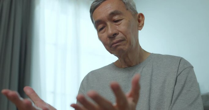 Asian senior man has tingling and numbness in his hand which causes beriberi. Mature asian man with wrist pain at home.