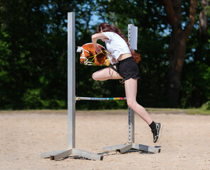 Girl jumping on hobby horse. Champion. Horse sport. Summer light. Green outdoor trees background....
