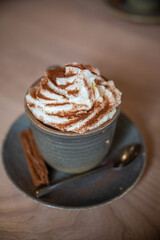 Cup of coffee with cream and cacao powder on it, chocolate next to it, vertical shot